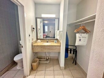 Bathroom with toilet. alcove with vanity unit, mirror, towel rail with towels, hairdryer, ironing board, portable folding luggage rack, hanging rail with hangers