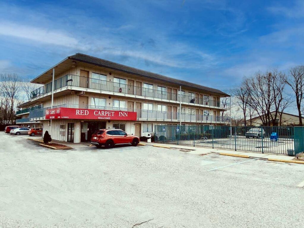 Hotel entrance, 3 story building with exterior guest room entrances, fenced in outdoor pool, parking spaces