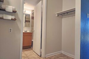 Shelves with towels, shelf with hanging rail, doorway to bathroom, tiled floor