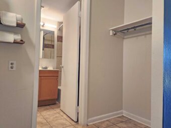 Shelves with towels, shelf with hanging rail, doorway to bathroom, tiled floor