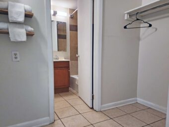 Shelves with towels, shelf with hanging rail and hanger, doorway to bathroom, tiled flooring