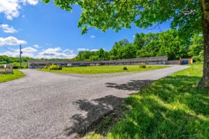 One story building, exterior guest room entrances, parking spaces, grassy areas and trees